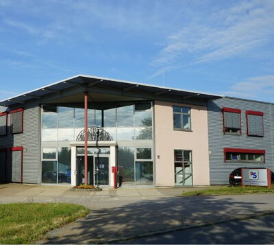 Modernes Gewerbegebäude mit großer Glasfassade, roten Akzenten und Metallverkleidung im Gewerbegebiet