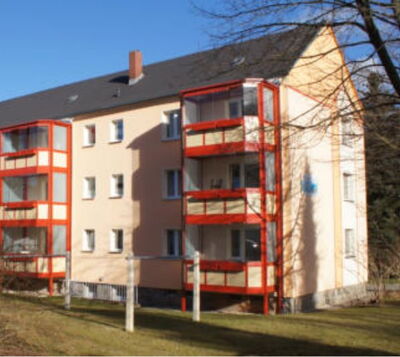 Mehrgeschossiges Wohnhaus mit heller Fassade und markanten roten Balkonkonstruktionen aus Stahl