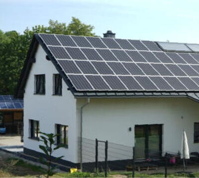 Weißes Einfamilienhaus mit großflächiger Photovoltaikanlage auf dem Satteldach