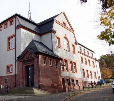 Historisches Gebäude mit roter Sandsteinfassade, Schieferdach und repräsentativem Eingangsportal mit Freitreppe